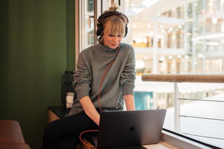 XMS 23 Frau mit Kopfhörer vor Laptop